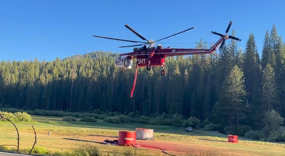 A Sikorski S-64 “Skycrane” firefighting helicopter dips its snorkel toward a tank of fire retardant chemicals to be dropped on hot spots of the Washburn Fire burning in Yosemite National Park and the Sequoia National Forest on July 14, 2022. The helicopter typically has a capacity of almost 2,700 gallons.