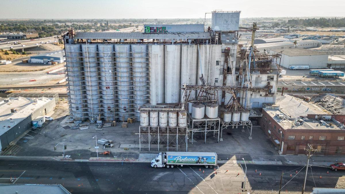 A Producers Dairy truck drives by the tall feed silos on H Street near Palm Avenue in Fresno on Wednesday, Aug. 28, 2024. The feed silos were once used by Zacky Farms and are now owned by Producers, which plans on demolishing them from the site they’ve stood at for nearly 80 years.
