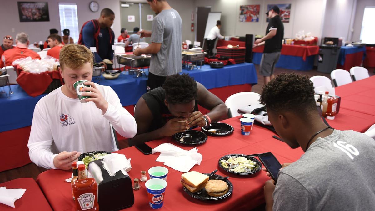 Fresno State football players Justin Rice, left, James Bailey, center, and Rian Fields, right, join other teammates for lunch after practice in trailers that act as a dining hall. The facility, and the healthy food that’s served there, are expected to be a factor in the Bulldogs sustaining their turnaround.