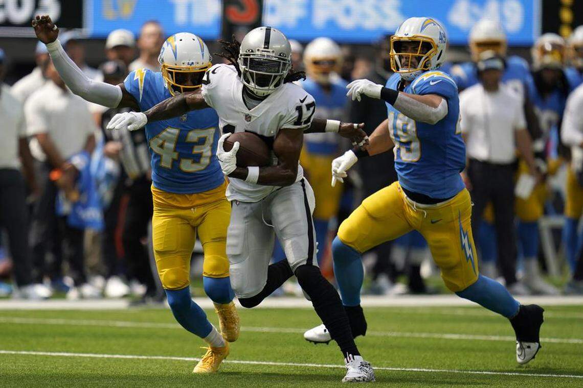 Las Vegas Raiders wide receiver Davante Adams runs in front of Los Angeles Chargers cornerback Michael Davis and linebacker Drue Tranquill during the first half of an NFL game in Inglewood, Calif., Sunday, Sept. 11, 2022.
