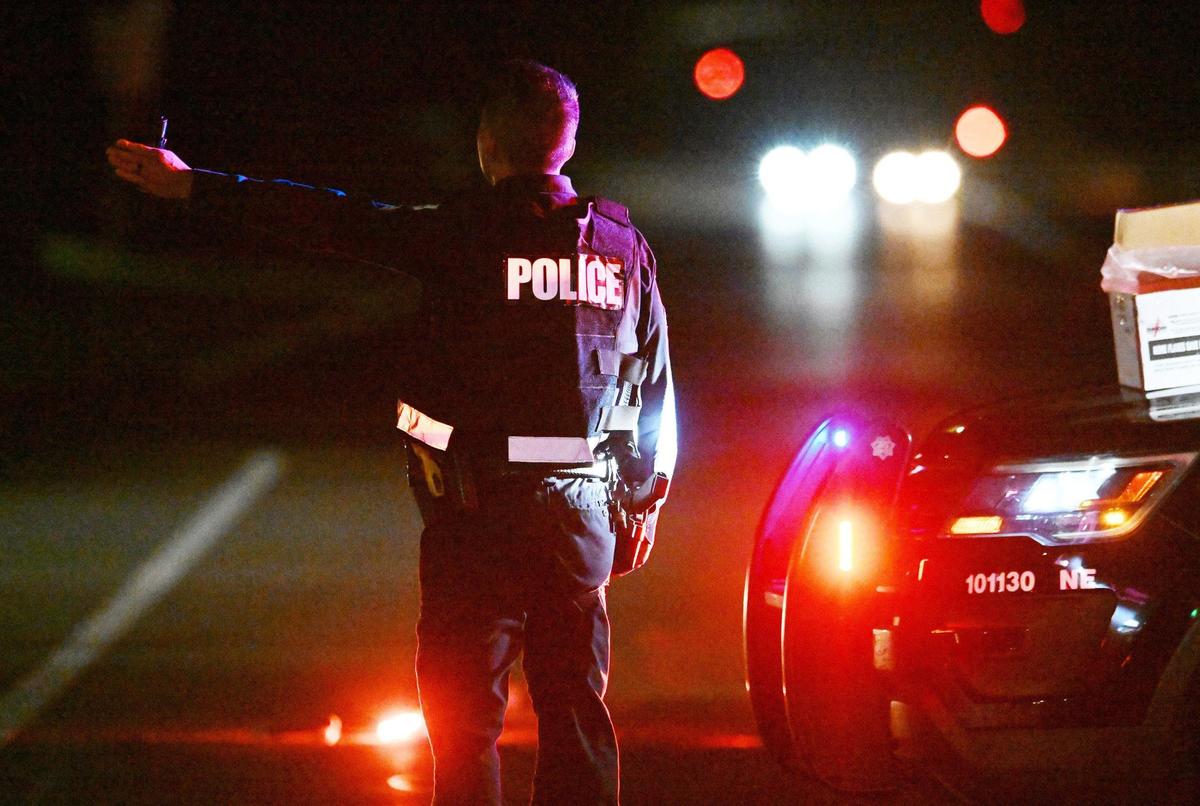 A Fresno police officer directs traffic from northbound Friant Road onto eastbound E Champlain Drive as emergency personnel respond to the scene of a multiple vehicle accident with fatalies along Friant Friday night, Oct. 13, 2023 in Fresno.