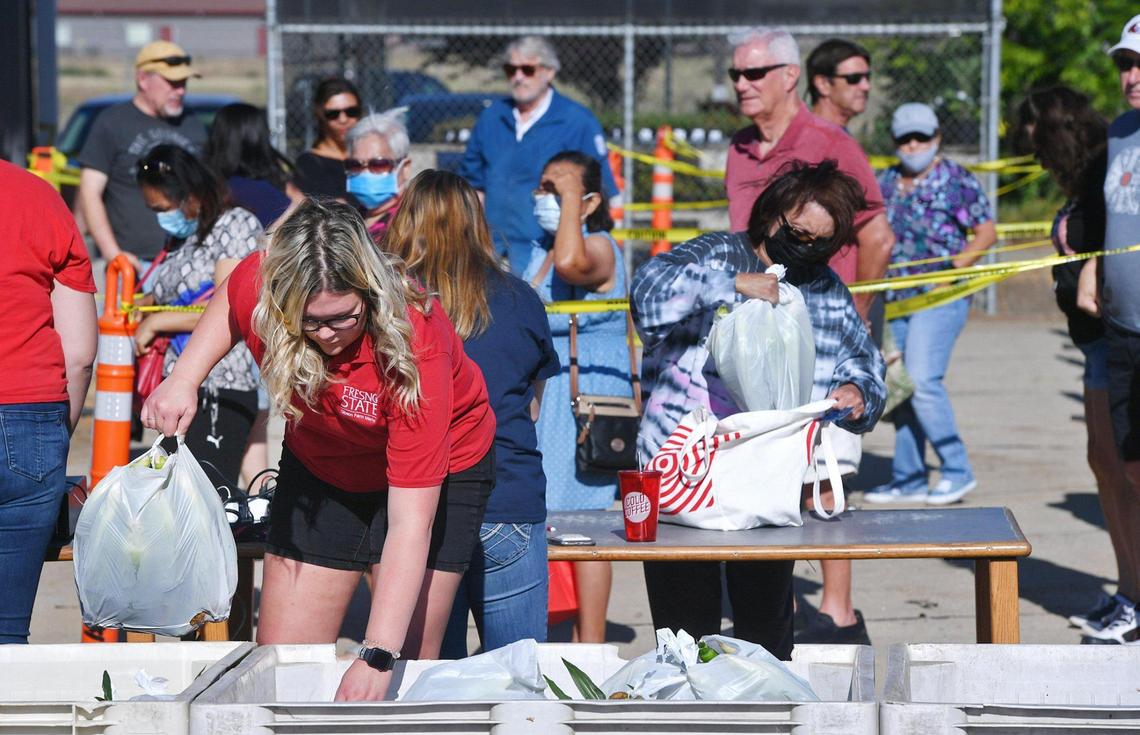 Courtney LeBar, student assistant, left, selects bagged corn for customers waiting outside on the first day Rue and Gwen Gibson Farm Market began selling the popular seasonal sweet yellow and white corn. Customers could still select individual ears of corn inside the market. Photographed Monday, May 30, 2022 in Fresno.