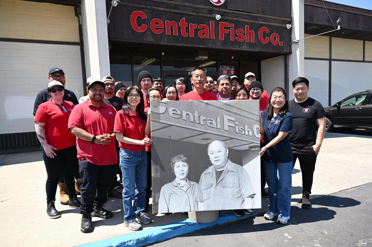 Morgan Doizaki, owner of Central Fish, center, poses with staff holding a photo of the original owners his aunt Nofuko Yokomi, left and uncle Akira Yokomi, right, outside the landmark business located in Chinatown on Tuesday, April 29, 2025 in Fresno.