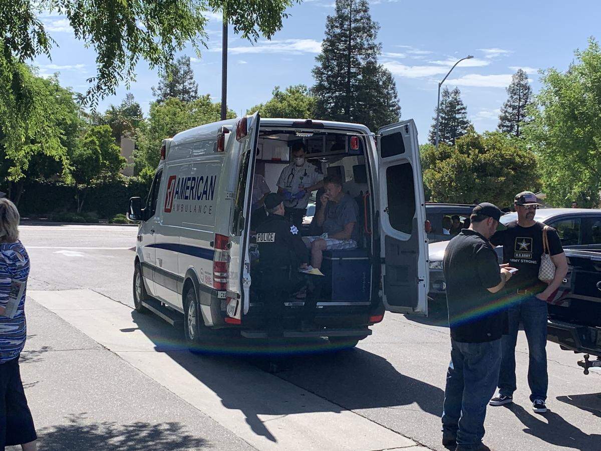 Emergency workers check out a man after a scuffle outside the Waffle Shop in northwest Fresno on Sunday. Police were involved in a brief clash with supporters of the restaurant, which has reopened in defiance of emergency city orders related to the COVID-19 pandemic.