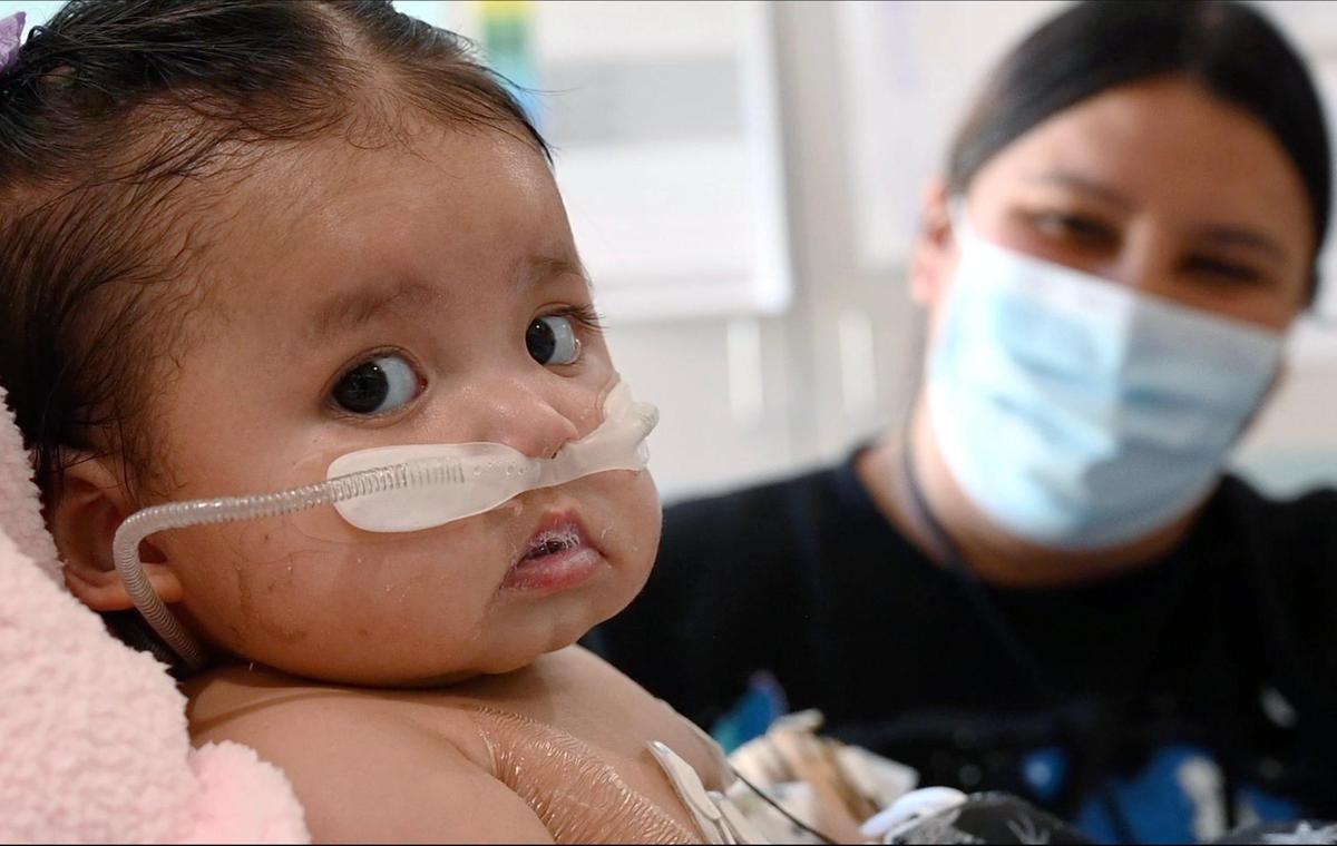 Victoria Saypen, who developed RSV, or respiratory syncytial virus, and was treated at Valley Children’s Hospital’s ICU, stares at the camera as her mother Wendy Batres watches Thursday, March 2, 2023 at the hospital in Madera County.