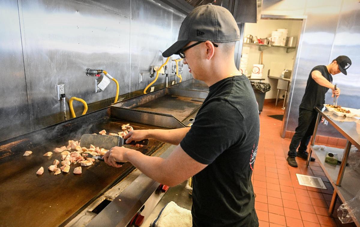 Kong Thao of Spicy Mayo Hibachi starts an order of chicken on the grill at their new restaurant on Shaw Avenue near West in Fresno on Tuesday, May 16, 2023.