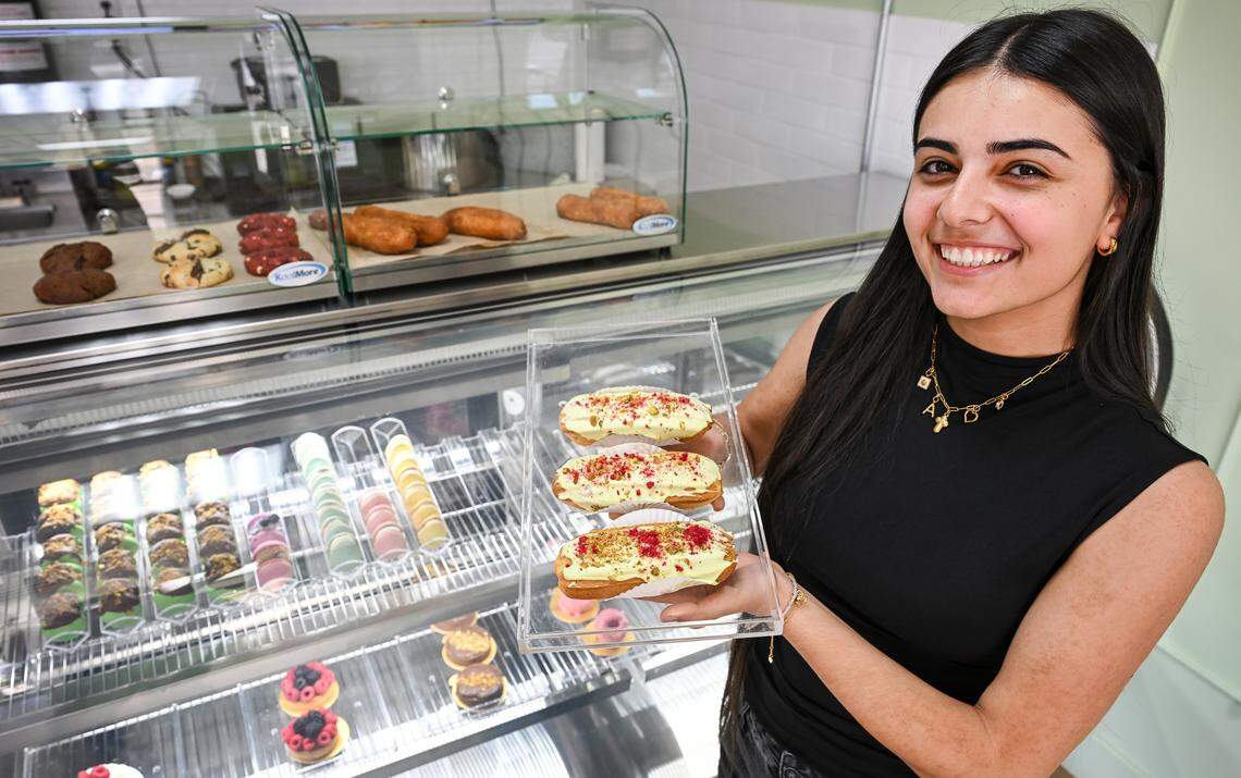 Arpi Keymetlyan holds up a trio of pistachio eclairs while standing in front of a case of various treats and baked goods at Lodei Bakery & Cafe, an Armenian family-owned bakery on the northeast corner of Palm and Bullard.
