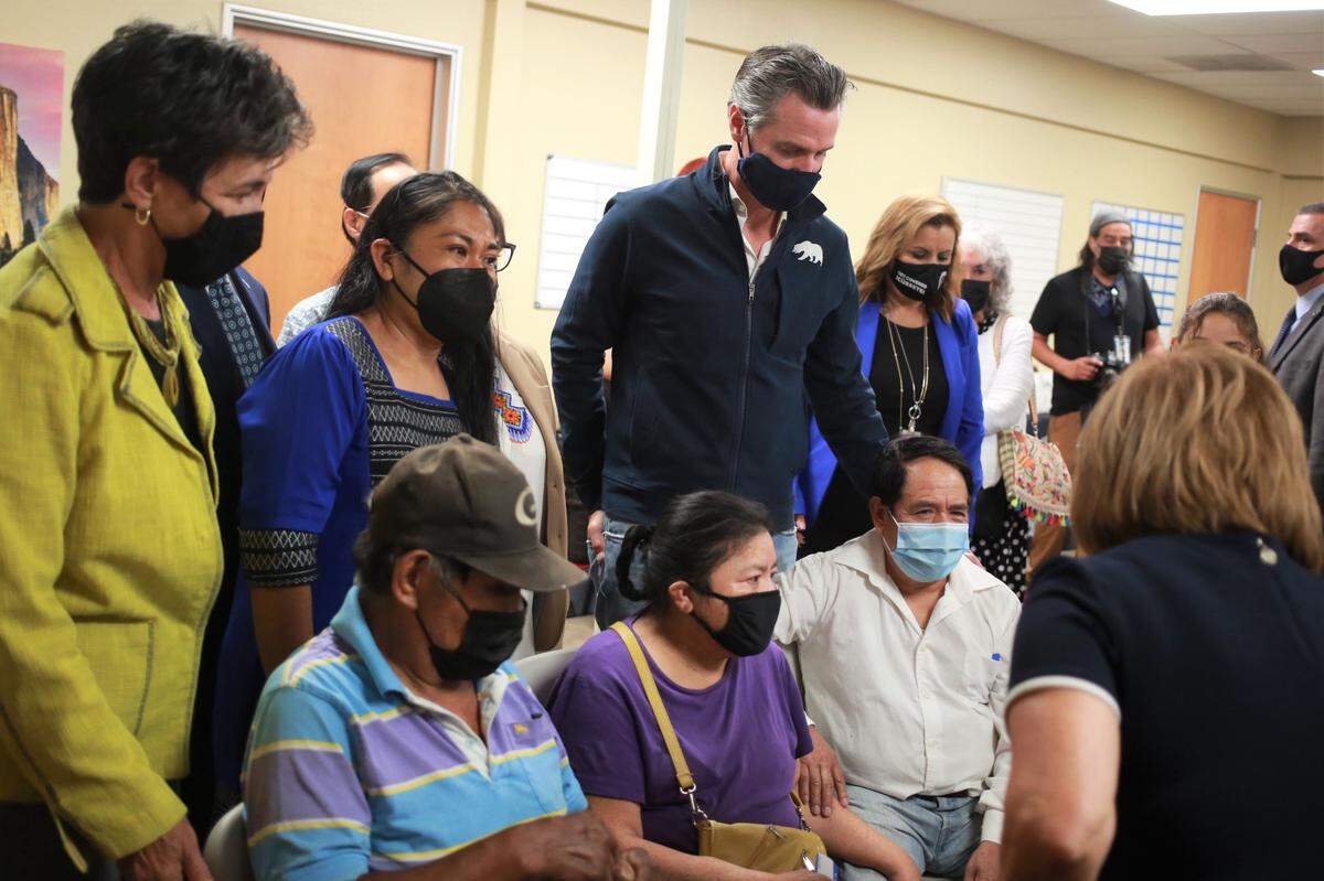 El gobernador de California, Gavin Newsom, en el centro, con líderes comunitarios y ex trabajadores agrícolas después de firmar el proyecto de ley que amplía la cobertura de atención médica para los residentes de California indocumentados en la Clínica Sierra Vista el martes 27 de julio de 2021 por la mañana en Fresno, CA.