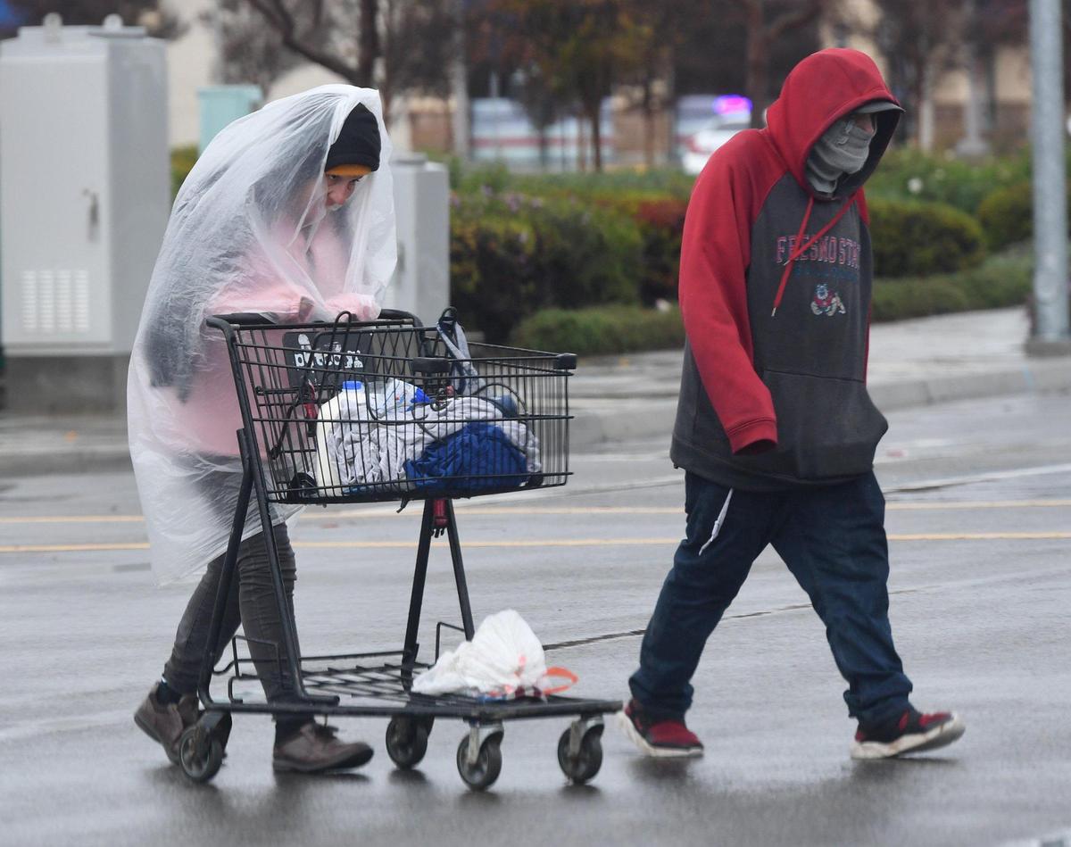 A couple walk through the rain after shopping at the Marketplace at El Paseo, during the storm Tuesday, Dec. 14, 2021.