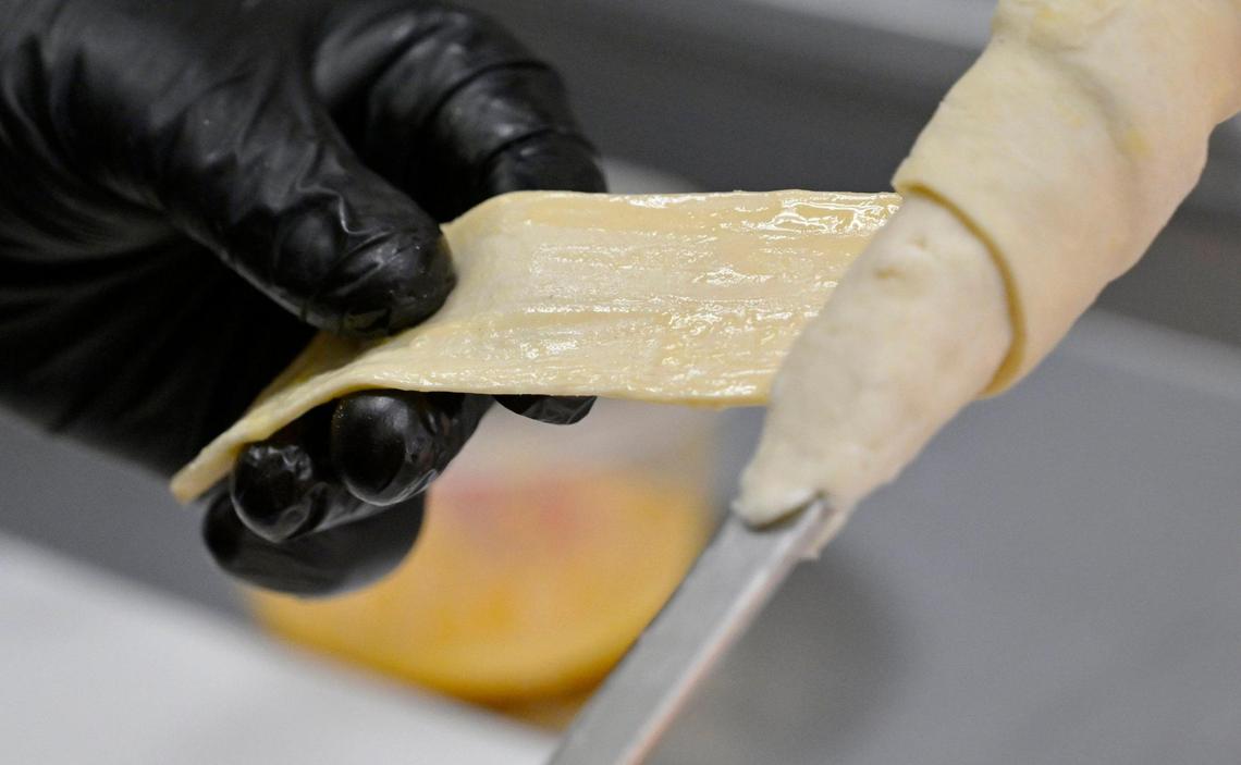 Dough is wrapped around a skewer holding meat or cheese before grilling at the new Cheesy Bread House located in the same shopping center as Costco on West Shaw Avenue. Photographed Friday, June 23, 2023.