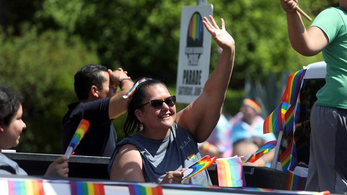 Juana Echeveste-Davis of Oasis Legal Services waves to spectators at the 2023 Rainbow Pride Parade in Fresno’s Tower District.