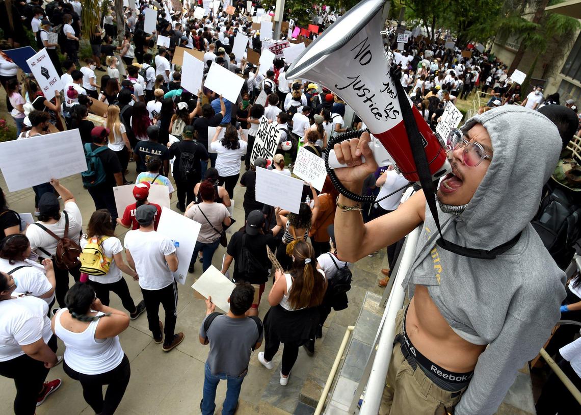 Eddie Wutangsy uses a bullhorn in chanting to the crowd of several thousand protesters as they march past Fresno Police headquarters during the protest over the death of George Floyd, May 31, 2020.
