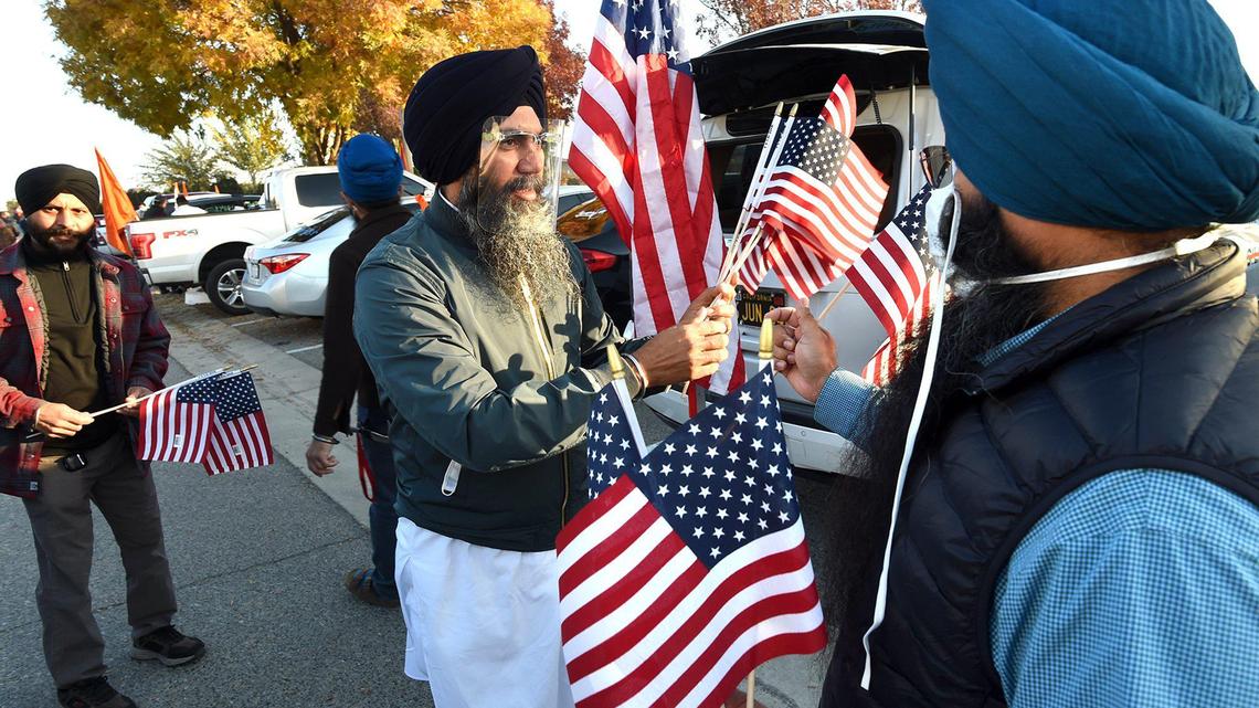 A Sikh man passes out flags at a rally at Gurdwara Gur Nanak Parkash near Fowler, Saturday morning, Dec. 5, 2020, before a convoy of about 250 vehicles to Oakland for a protest at the Indian ConsulateÕs office to demonstrate against Indian Prime Minister Narendra Modi and the treatment of farmers in India over changes to the agricultural system there. The protest, reflecting the massive civil unrest in the Punjab region, involves three new laws which would open the government-controlled agriculture market to corporate farming. Several cities in the Valley, including Fresno, Bakersfield, Tracy and Livingston, were taking part in the Oakland protest.