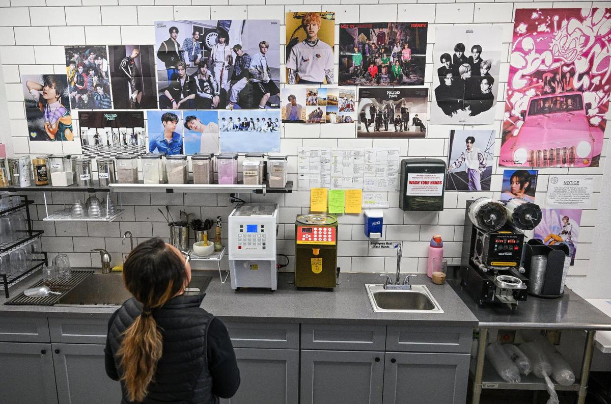 Owner Sengphiane Kim looks up at all of the K-pop posters covering the wall before preparing a couple of boba teas at Bubble Pop Tea in Fresno.