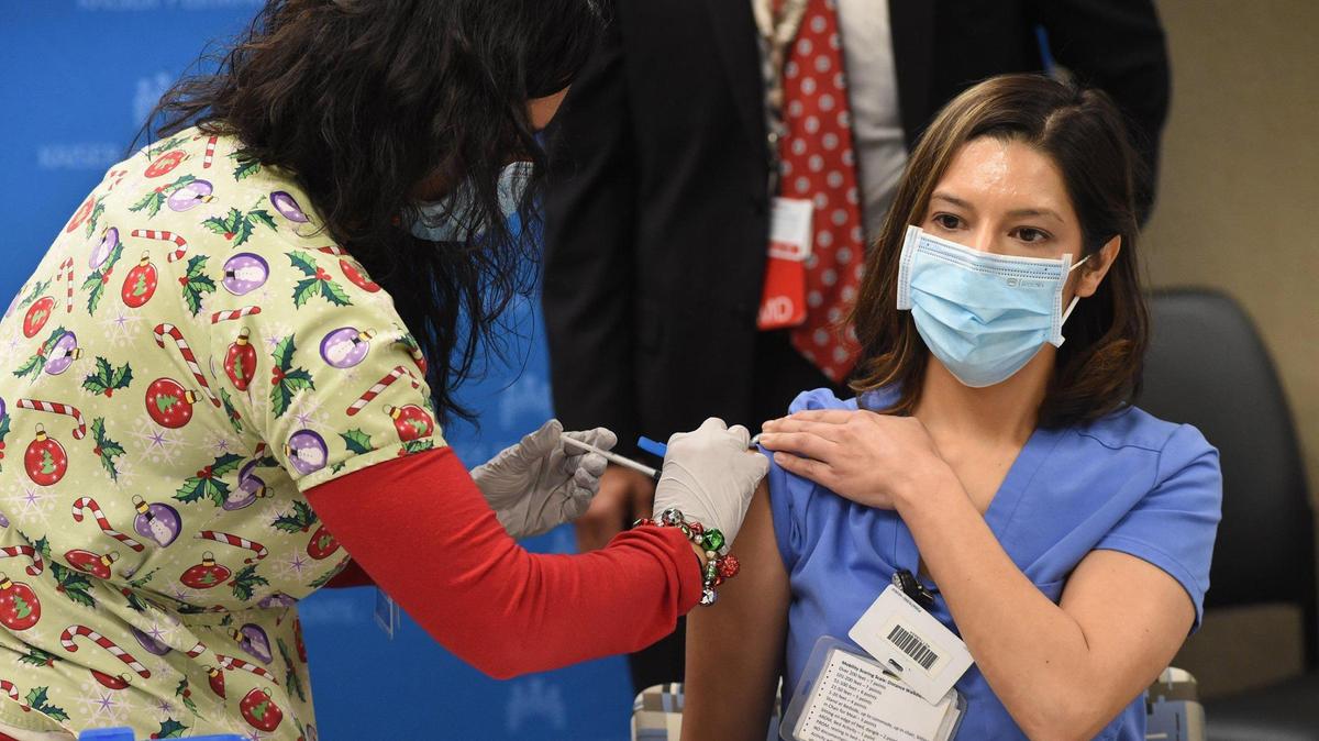 Kaiser Permanente Fresno registered nurse Juliana Day, who cares for patients in the hospital’s COVID-19 unit, receives the first COVID-19 vaccination at the hospital from RN Leticia Ramirez on Dec. 17, 2020, in Fresno.