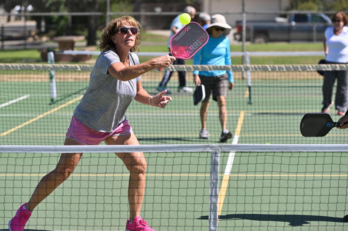Laurie Werner returns the ball in a doubles pickleball game played on a tennis court at Rotary East Park Wednesday morning, June 21, 2023 in Fresno. Although surrounding towns have dedicated pickleball courts, Fresno and Clovis area fans of the game must share the use of tennis courts with added pickleball lines.