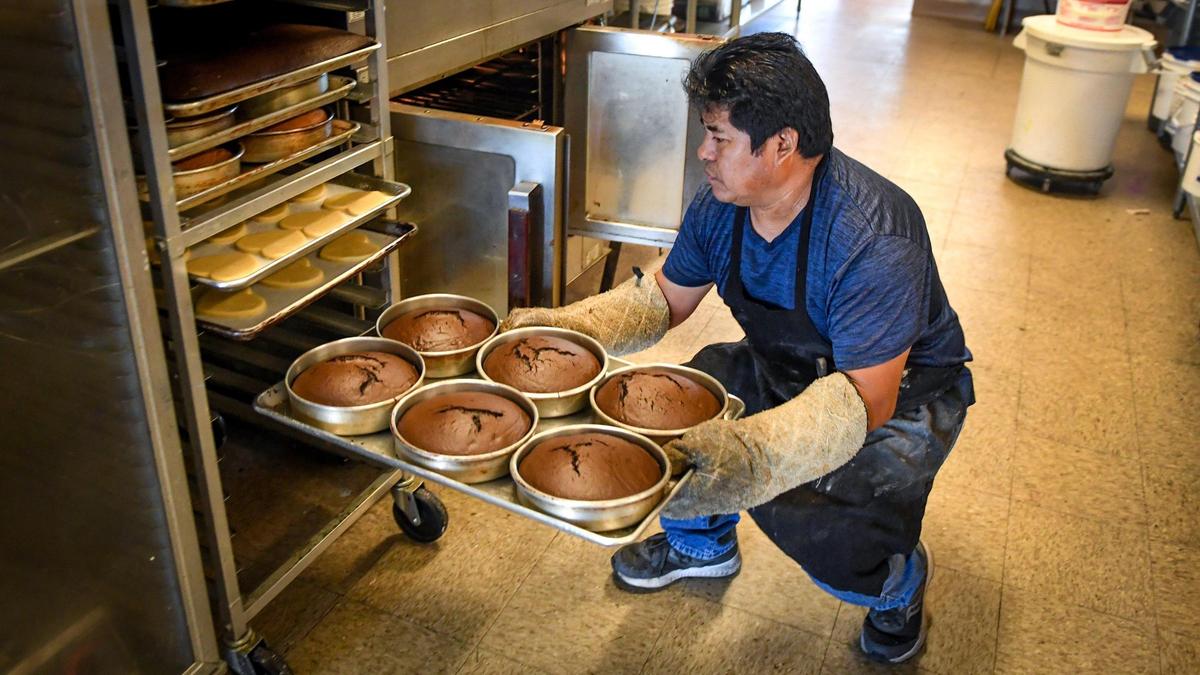Marcello Maya, of Callejas Cakes in Fresno, takes freshly baked cakes out of the oven while working at the shop on Tuesday, April 20, 2021.