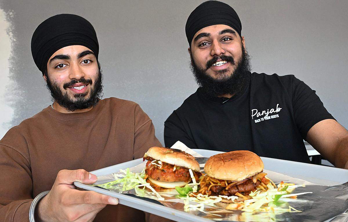Pavitar Singh, owner, left, and manager Taran Singh, right, hold two of their vegetarian burgers including the Punjabi Noodle Burger to the right at Rangla Punjab Restaurant & Sweets Friday, Oct. 17, 2025 in Fresno.