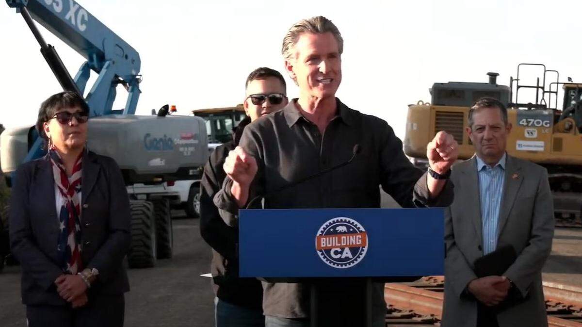 California Gov. Gavin Newsom, center, is flanked by Kern County Supervisor Leticia Perez, left, high-speed rail construction worker Anthony Canales, and High Desert Corridor Joint Powers Authority executive director Arthur Sohikian, right, at the site for a new railhead to be built near Shafter to lay tracks for the state’s bullet-train line through the San Joaquin Valley, on Monday, Jan. 6, 2025.