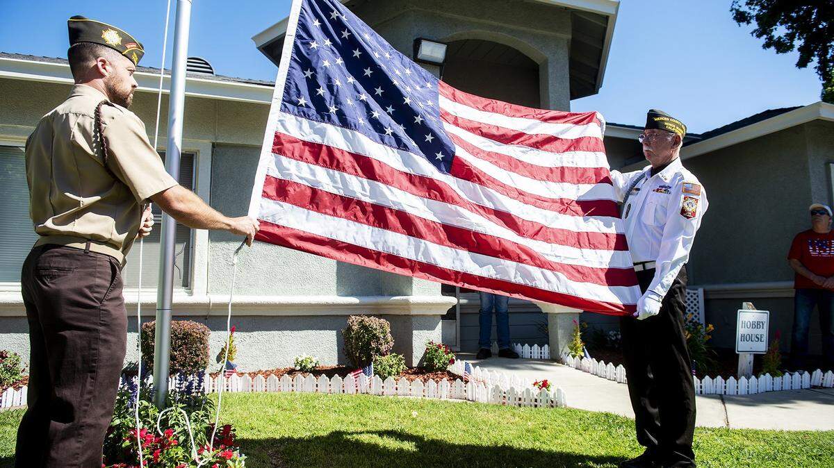 Members of the Winton VFW, Adam Conour, left, and Steve Berkenkamp, right, unfurl an American flag during a ceremony inside the Castlewood community in Atwater, Calif., on Tuesday, June 14, 2022.