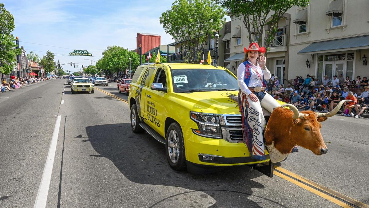 Miss California Rodeo Salinas Mayson Bothwell rides on the hood of a van mounted with a bull head while cruising down Clovis Avenue during the 109th annual Clovis Rodeo Parade on Saturday, April 29, 2023.