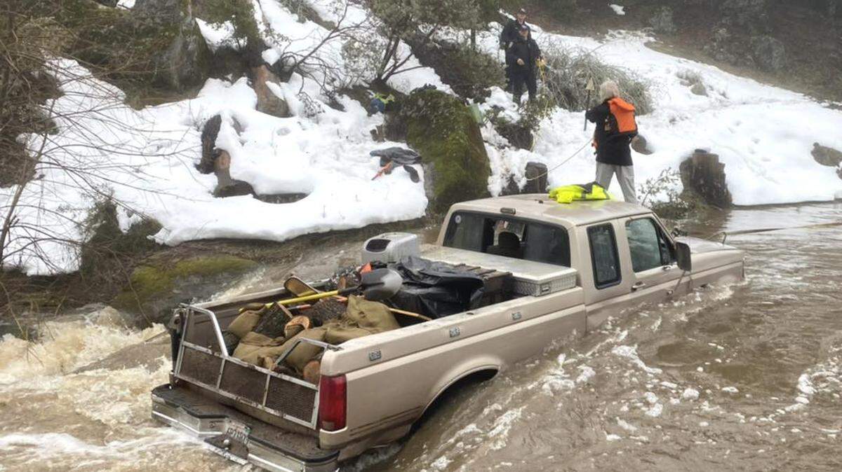 Crews with the Madera County Sheriff’s Office come to the aid of a driver who tried to take his pickup truck across a flooded roadway on a mountain road in the eastern part of the county on Friday afternoon, March 10, 2023. The man was brought to safety without injury.