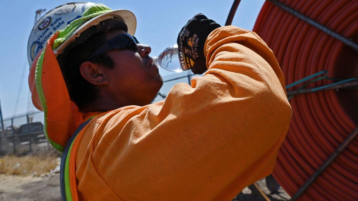 Jorge Bacerra takes a drink of water from a bottle in his vest as the temperature reaches 106 degrees along Weber Avenue near Roeding Park in September 2022.