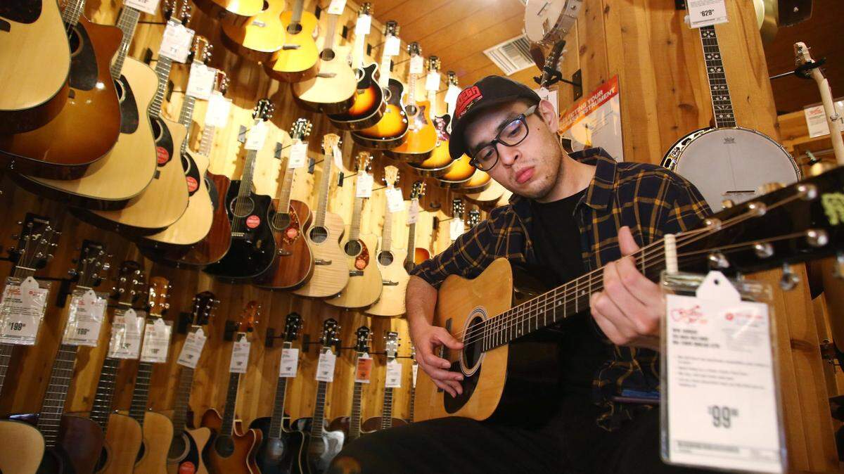 Abraham Jimenez tries out an acoustic guitar at Guitar Center, winner of best Musical Merchandise for People’s Choice, shown Tuesday, March 10, 2020 in Fresno, Calif.