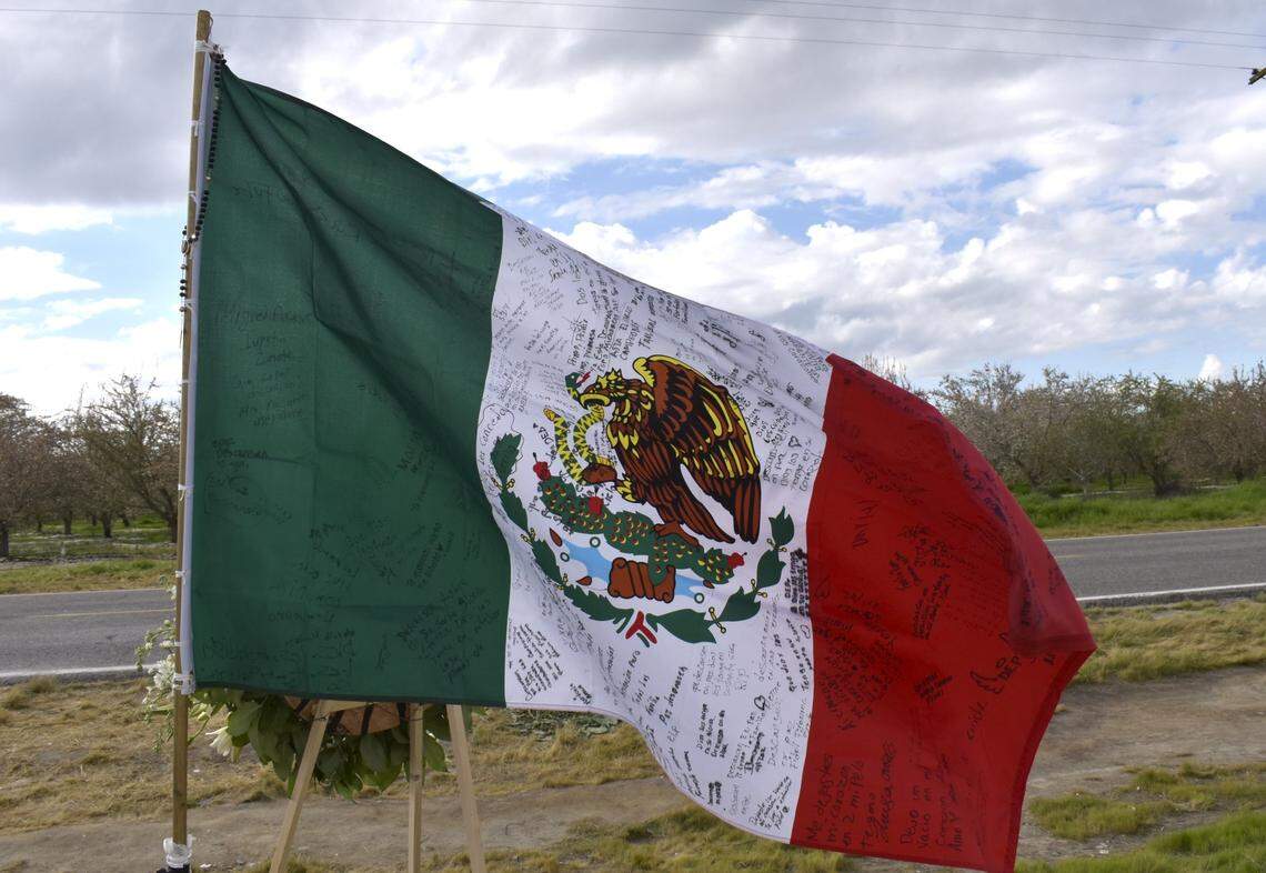 Una bandera mexicana que ondea en la instalación en homenaje a los trabajadores agrícolas de Madera contiene mensajes escritos en español en los que se leen frases como "descansen en paz" y "que Dios los tenga en su santa gloria." Los siete trabajadores agrícolas fallecidos en el accidente ocurrido en Madera el 23 de febrero eran de México.