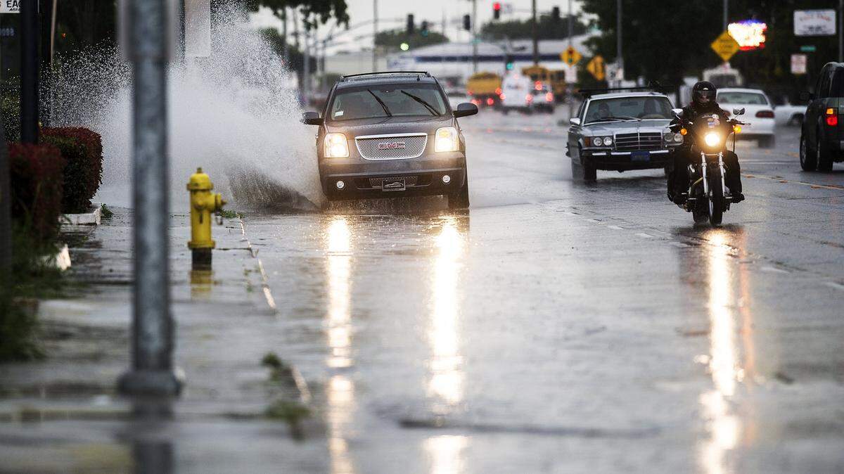An SUV drives through standing water in the flooded right lane of Martin Luther King Jr. Way during a heavy rainstorm in Merced, Calif., Thursday, May 7, 2015.