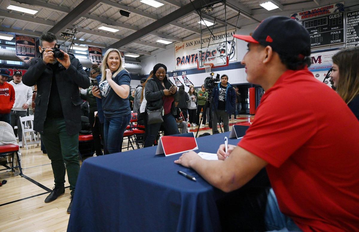 San Joaquin Memorial’s Brandon Ramirez, right, has his photo taken by supporters after signing ceremony to Fresno State Wednesday, Dec 21, 2022 in Fresno. Ramirez is The Bee’s Player of the Year.