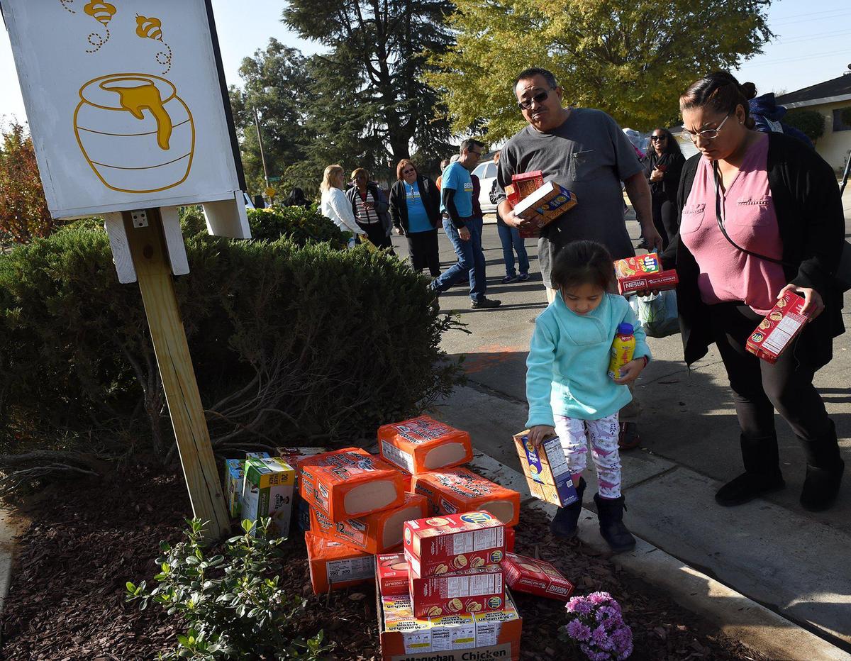 Evelyn Velasquez, 4, granddaughter of homicide victim Guadalupe Rivera, and family members deliver food to Fresno’s first Little Free Pantry, dedicated to Rivera, Wednesday morning, Oct. 30, 2019.