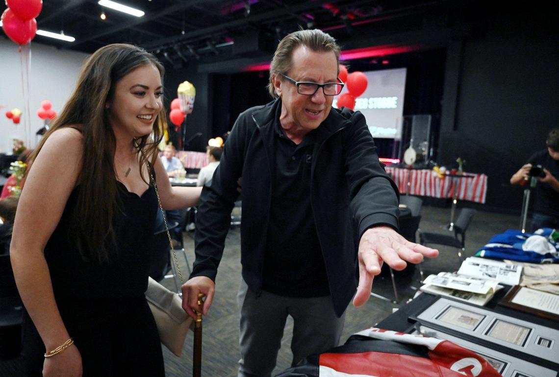 Fresno Christian journalism adviser Greg Stobbe, right, looks over the memorabilia gathered and on display after arriving at a surprise party where he was later honored with the Columbia Scholastic Press Association’s Charles R. O’Malley Award for excellence in teaching Friday, April 29, 2022 in Fresno. As part of the over 2 hour program, students inspired by Stobbe in the past spoke to those gathered or sent video messages of gratitude and appreciation, displayed on a large screen to about 100 attendees in the Student Ministry Center at Fresno Christian.
