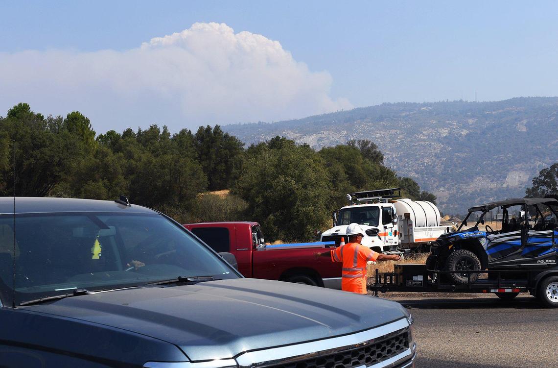 Caltrans worker directs traffic as residents are evacuated and roads closed for a wildfire, smoke seen in background, Saturday, Sept. 5, 2020 near Shaver Lake. The fire, reported at 2,000 acres and zero containment, was reported Friday night around 6:30 p.m.