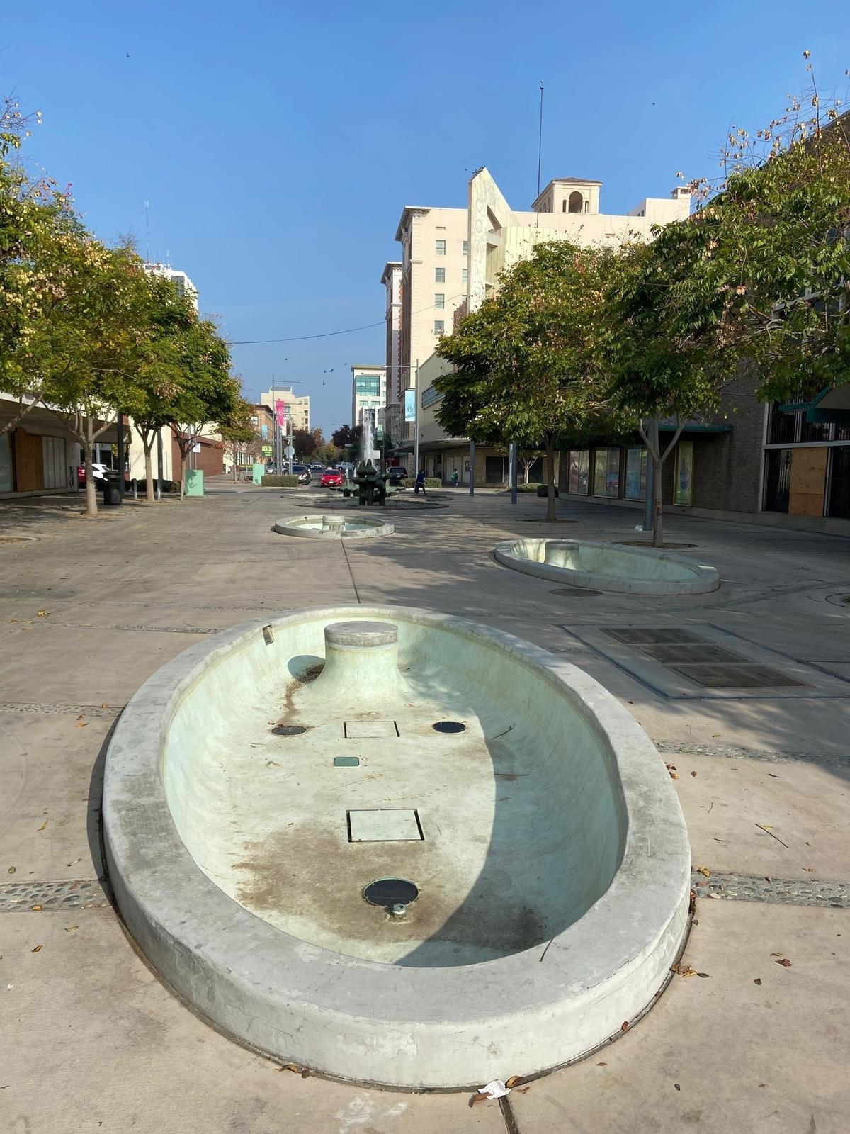 Three cement pools designed to showcase copper sculptures by 20th century California artist Claire Falkenstein sit empty in Kern Street Plaza in downtown Fresno, California on November 17, 2021. The sculptures were removed after being damaged by metal thieves.