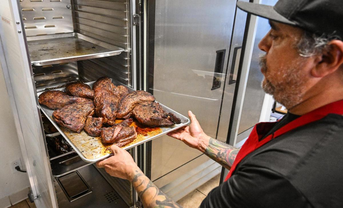 Bernard Mendoza looks over several smoked tri-tip roasts ready for the evening crowd at BenSmokin BBQ in Fresno on Wednesday, July 12, 2023.