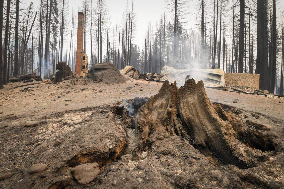 A tree stump smolders in front of a burned cabin in the Camp Silver Fir area on the north of Huntington Lake on Sunday, Sept. 13, 2020. Fire officials said a fire tornado blew through the area at some point last week burning cabins and knocking down many trees.