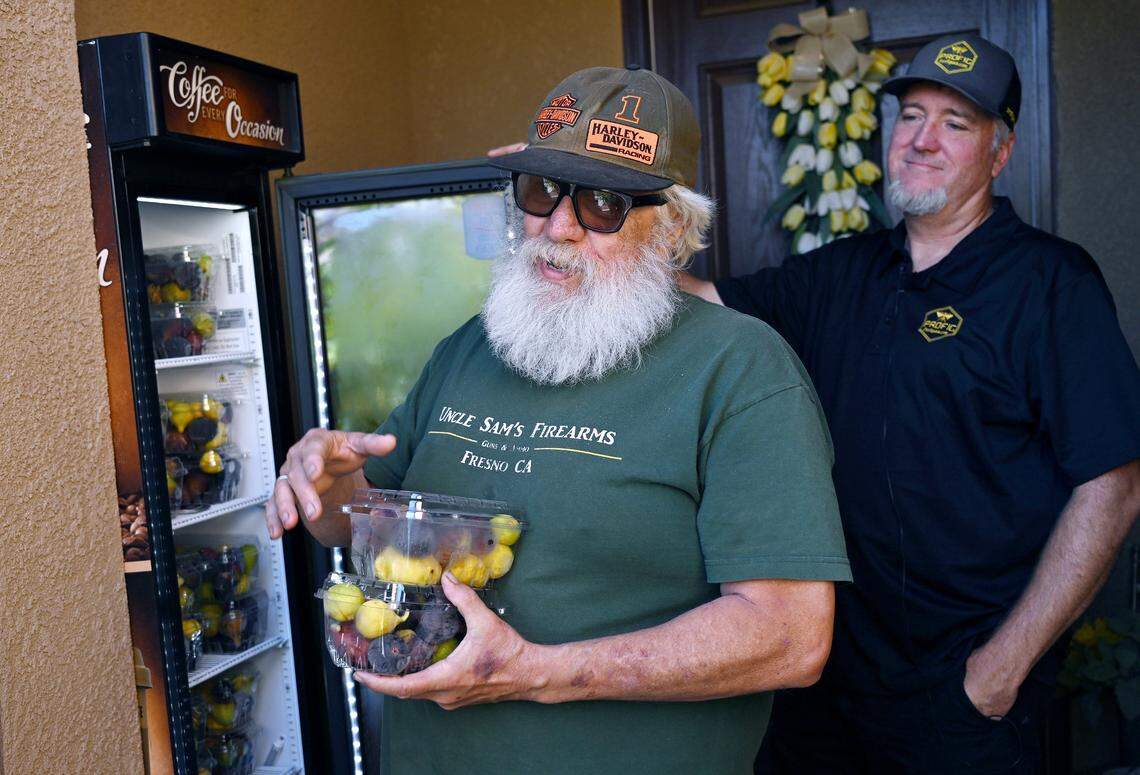 Customer Hal Cooksey, left, talks about his family's love for figs after he chooses two small boxes of figs from Brian Melton's storage case Wednesday, Aug., 13, 2025 in Fresno. Melton has cultivated a following on social media selling ripe packaged figs of various varieties from his front porch. 
