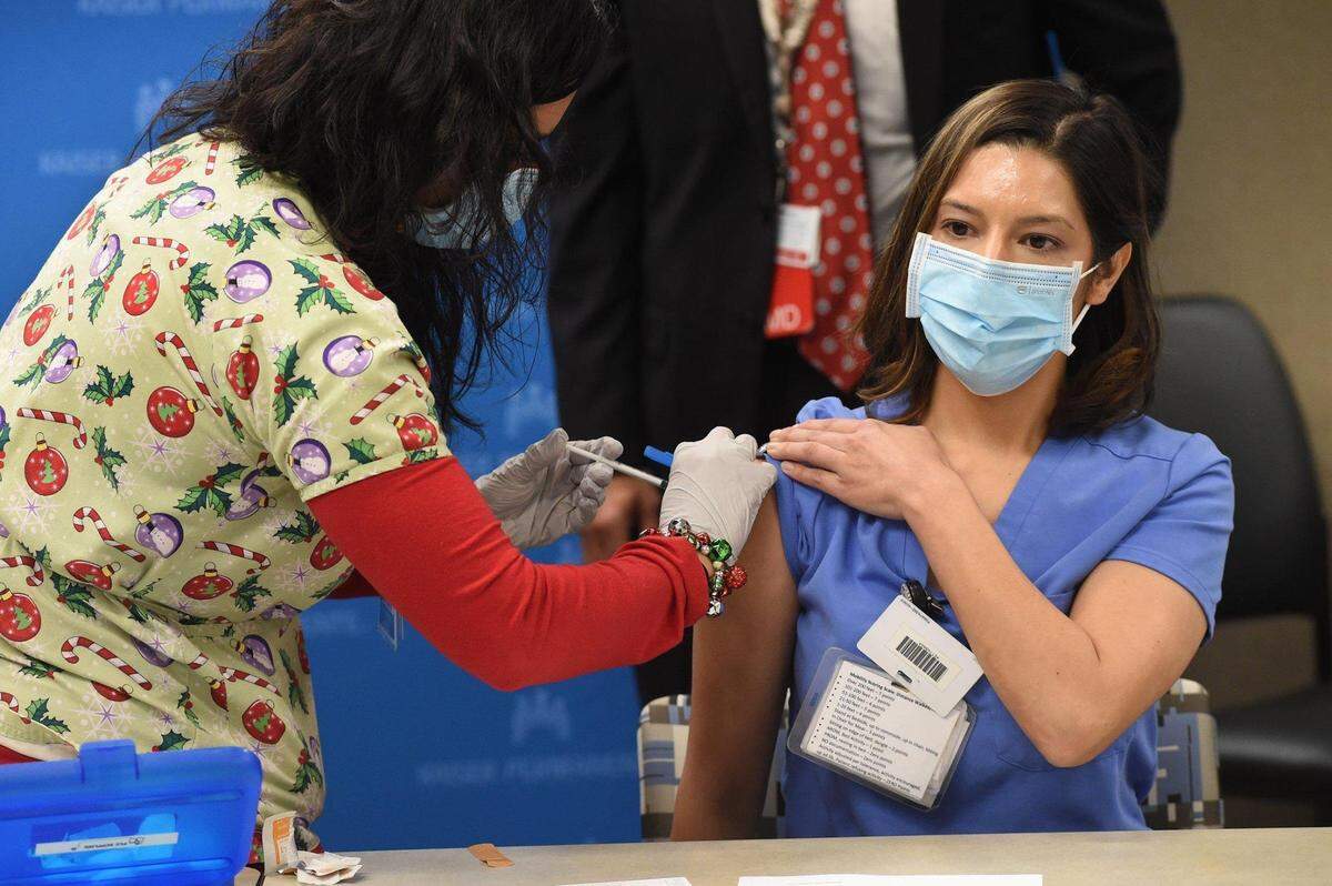 Kaiser Permanente Fresno registered nurse Juliana Day, who cares for patients in the hospital’s COVID-19 unit, receives the first COVID-19 vaccination at the hospital from RN Leticia Ramirez on Dec. 17, 2020, in Fresno.