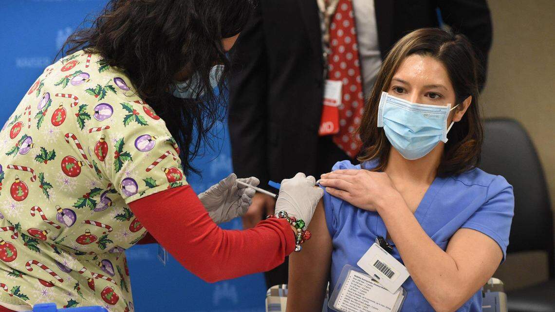 Kaiser Permanente Fresno registered nurse Juliana Day, who cares for patients in the hospital’s COVID-19 unit, receives the first COVID-19 vaccination at the hospital from RN Leticia Ramirez on Dec. 17, 2020, in Fresno.