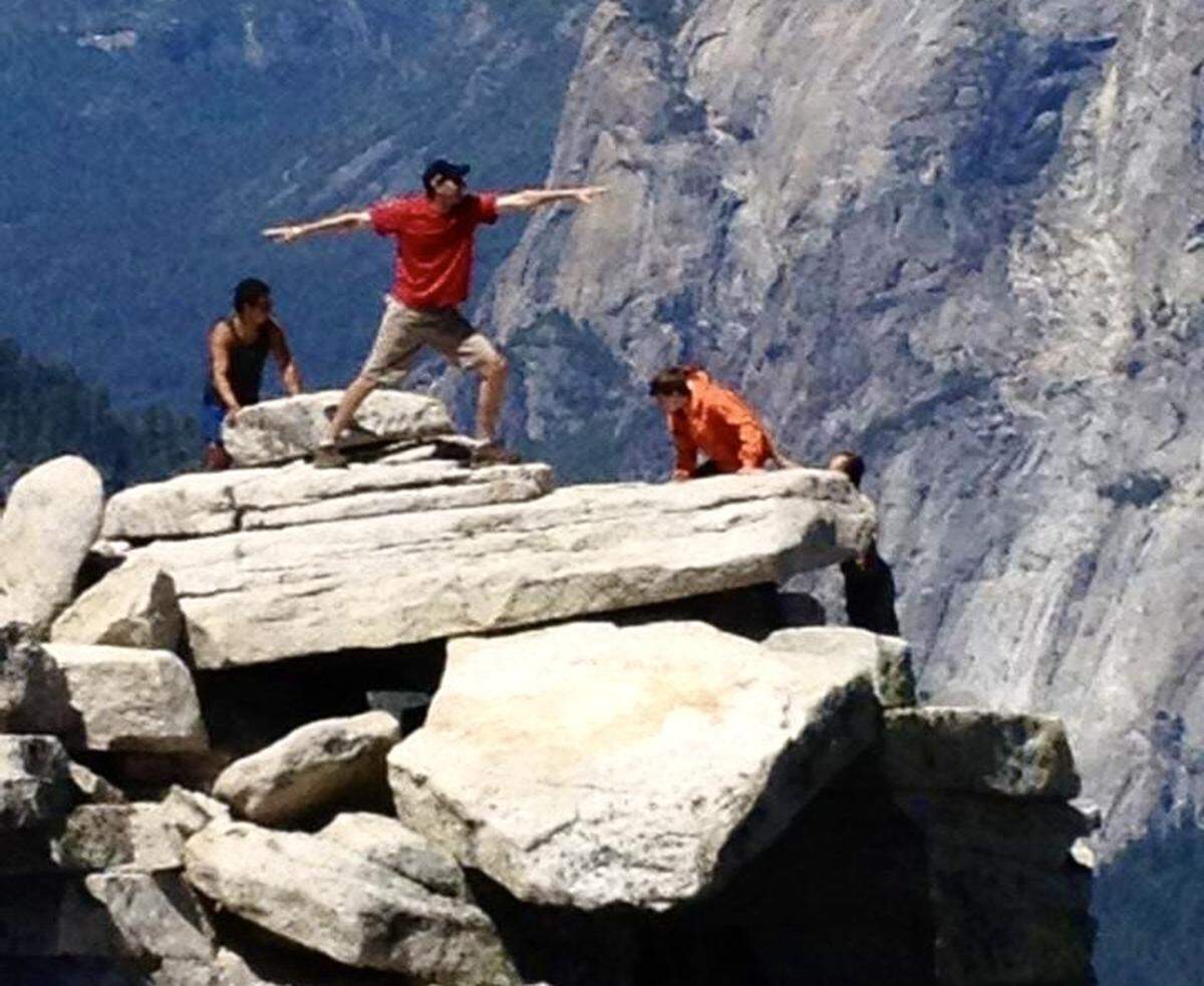 A hiker who climbed the cables to reach the top of Yosemite National Park’s Half Dome does a yoga pose near the edge of the summit. 