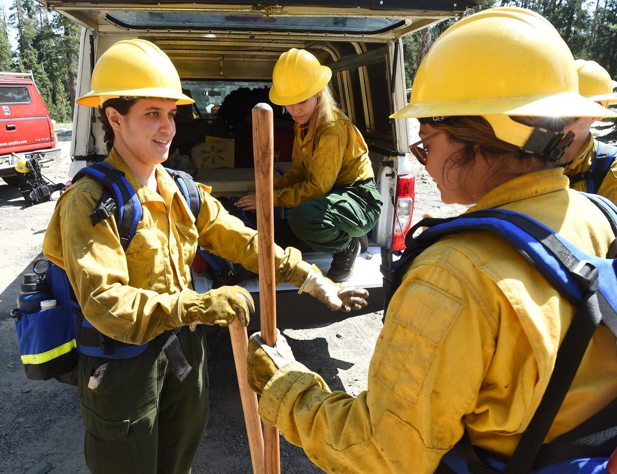 Guadalupe Ruiz, left, hands fire-fighting tools to Alma Caballero, as Rocio Macias, in background, unloads their truck, at the Yosemite Women’s Fire Internship members head to back-burning training on County Line Fire, July 14, 2021. The team members, who are interns, learned how to set back burns using drip torches and fuses (flare-type ignitors) to contain the fire. The Yosemite Women’s Fire Internship, the first-ever California Conversation Corps internship program of its kind, brings women together for a 10-week intensive program where they learn how to be firefighters and how to protect and manage the landscape with fire. In this internship, they learn key wildfire management skills such as sawing down trees, building piles for fuel removal, and other key skills for fire management.