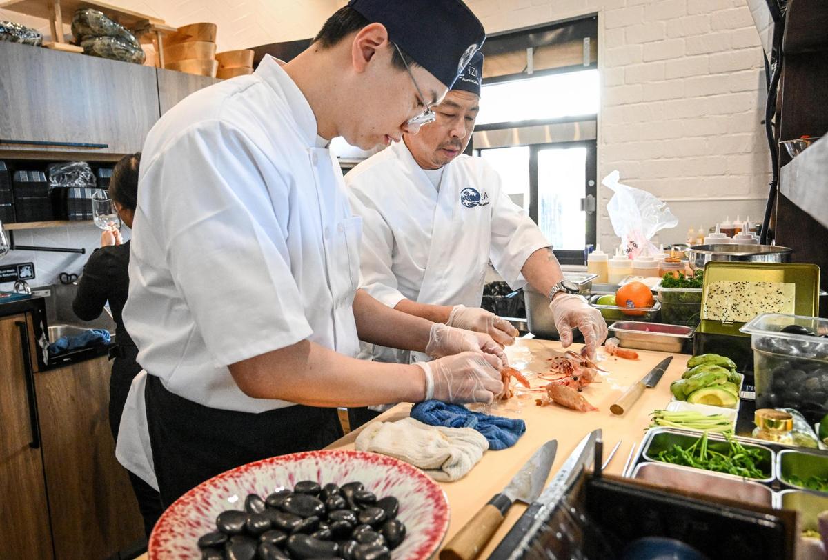Head sushi chef Elvis Wei, left, and Ejony Herliyono prepare specialized sushi dishes at the raw bar at O-iza Japanese Cuisine in the River Park shopping center.