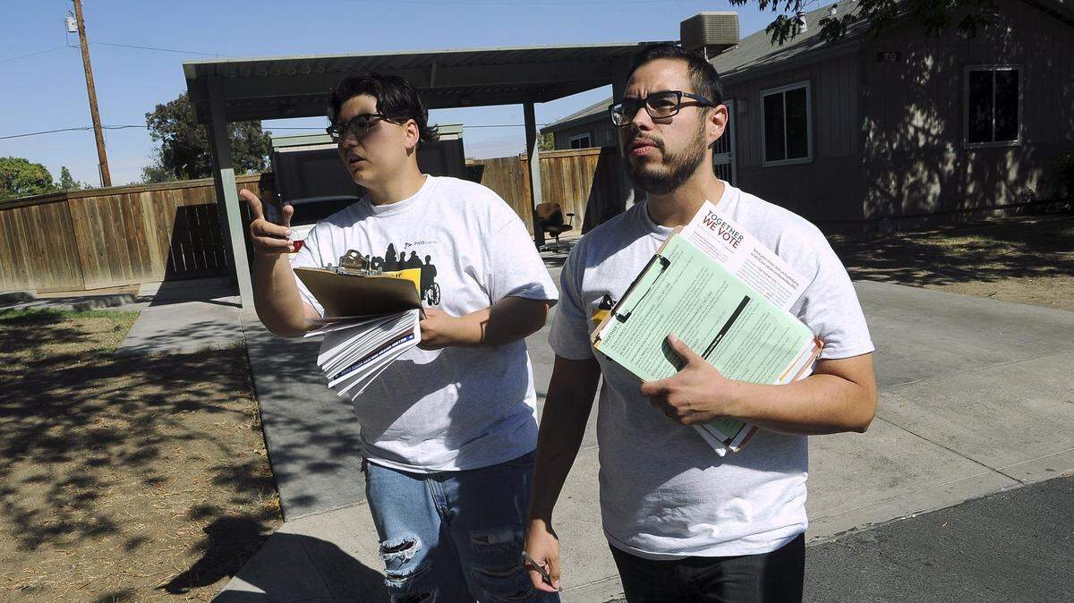 Volunteer Jadon Gutierrez, left, points down the block as he and Uziel Jimenez, right, search for latinos living in an apartment complex to encourage voting in 2016 in Fresno.