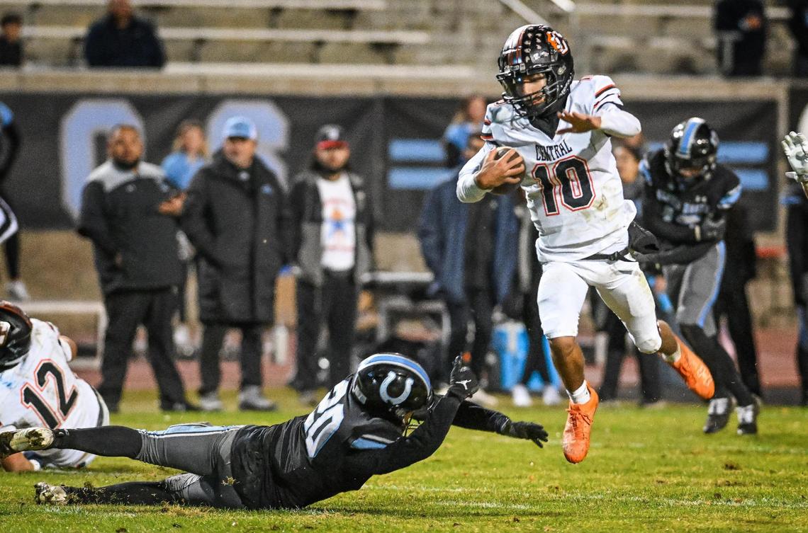 Central quarterback Jelani Dippel, right, leaps past Clovis North’s Wyatt Johnson before dashing into the end zone for a touchdown on a keeper during their Central Section Division 1-AA semifinal game at Veterans Memorial Stadium in Clovis on Friday, Nov. 15, 2024.