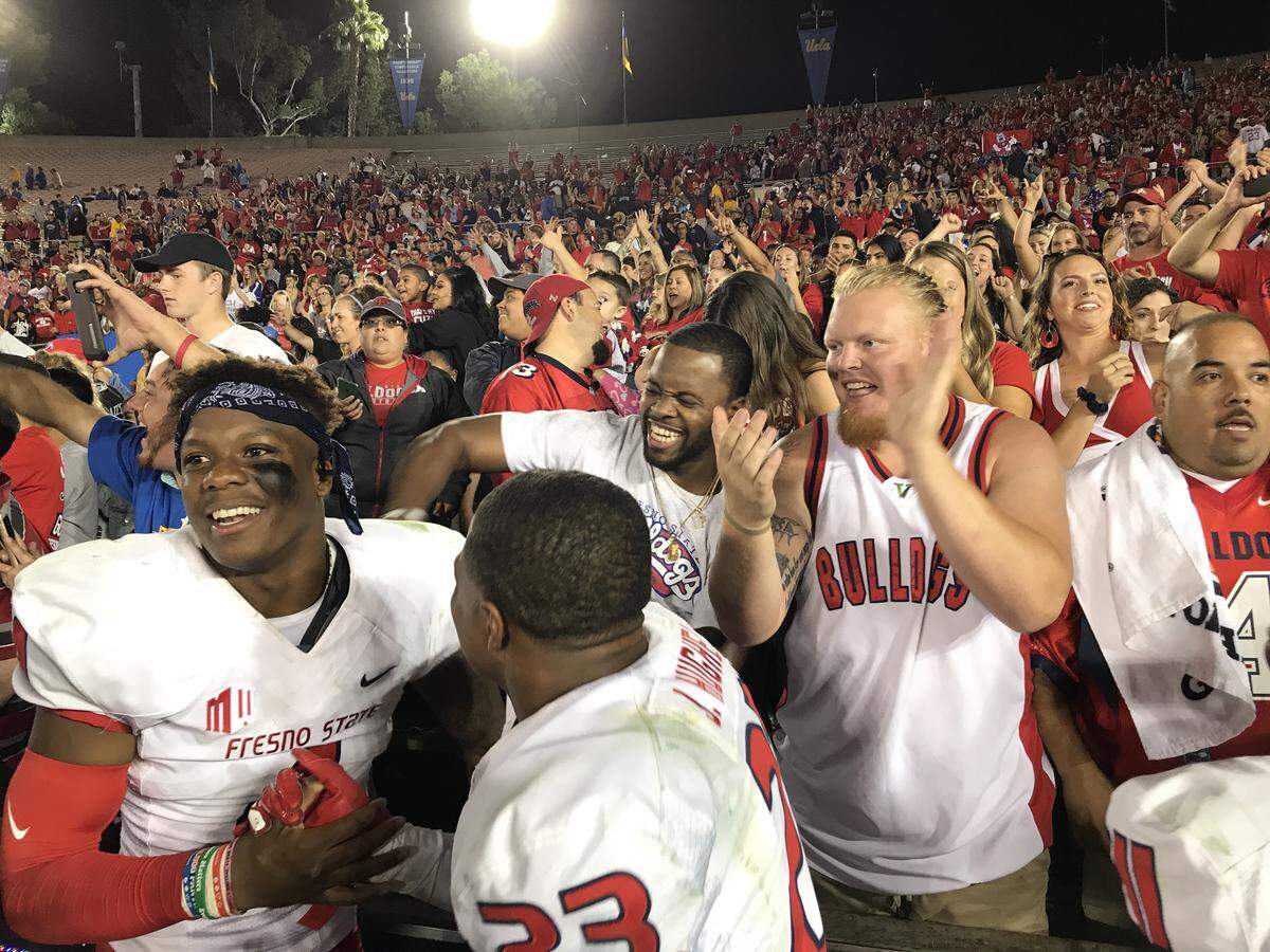 Fresno State Bulldogs including Mike Bell, left, and Juju Hughes celebrate after a 38-14 victory over UCLA at the Rose Bowl with former players DeShawn Potts and Aaron Mitchell (in white tank top) on Saturday, Sept. 15, 2018.