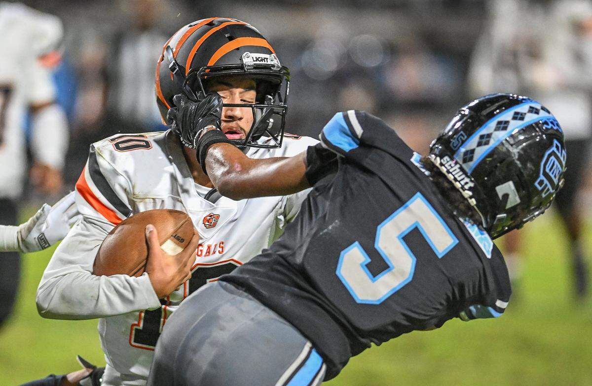 Central East quarterback Jelani Dippel gets pulled down by Clovis North's David Williams after a long gain on his feet against the Broncos during their TRAC opener at Veterans Memorial Stadium in Clovis on Thursday, October. 2, 2025.