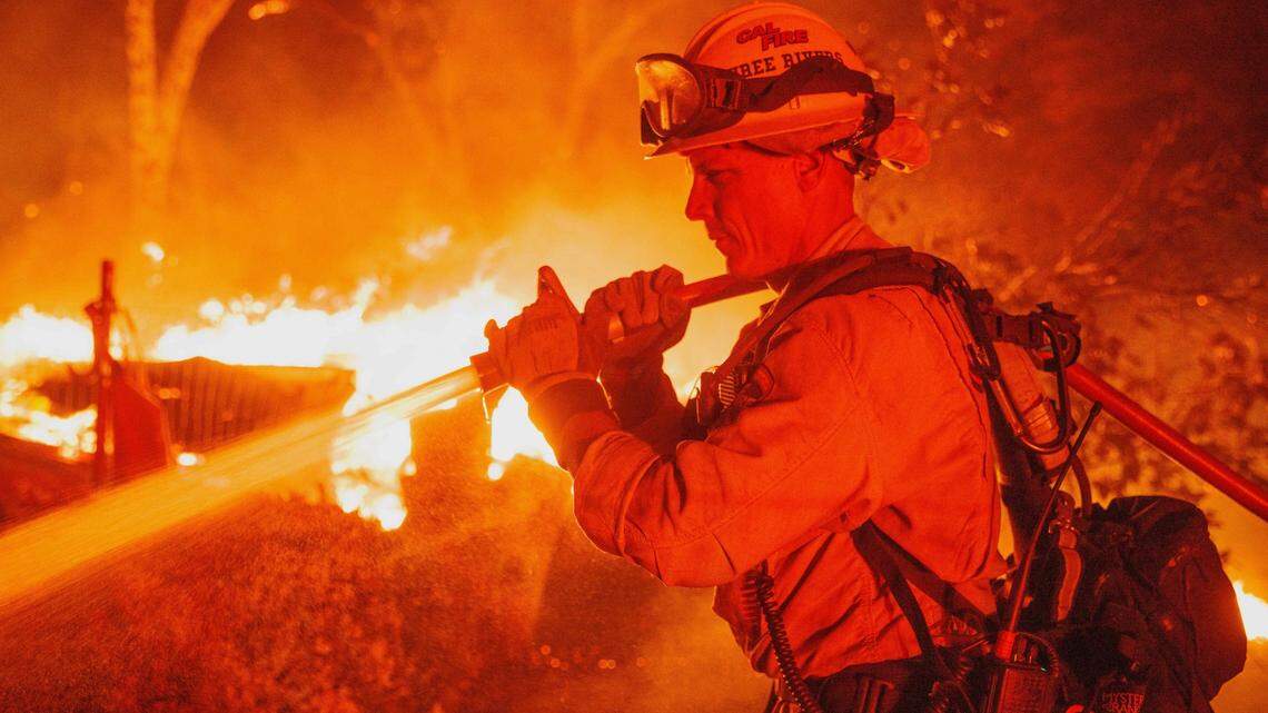 Firefighter Justin Montgomery defends a home on Triangle Road as the Oak Fire burns in unincorporated Mariposa County, Calif., on Friday, July 22, 2022.