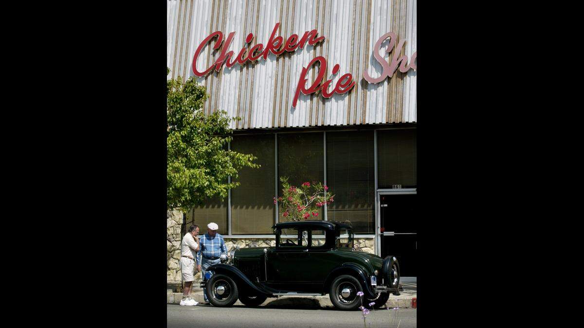 Sam Farrar, 76, far left, gets a close look at Bill Bryant's dark green 1930 Model A Ford Deluxe Coupe outside the Chicken Pie Shop in Fresno' s Tower District in this file photo from 2004.