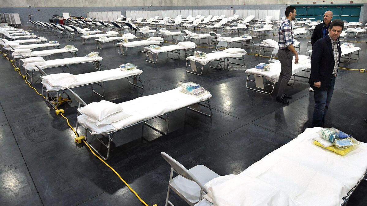 Fresno County Supervisor Brian Pacheco, right, looks over one of the 265 cots set up by the state of California last year in the Fresno Convention Center Exhibit Hall as a possible overflow site for patients because of the coronavirus pandemic. Pacheco and other leaders toured the site in April 2020. The site was not needed even during a winter surge in hospitalizations in Fresno and the central San Joaquin Valley, and it has since been dismantled.